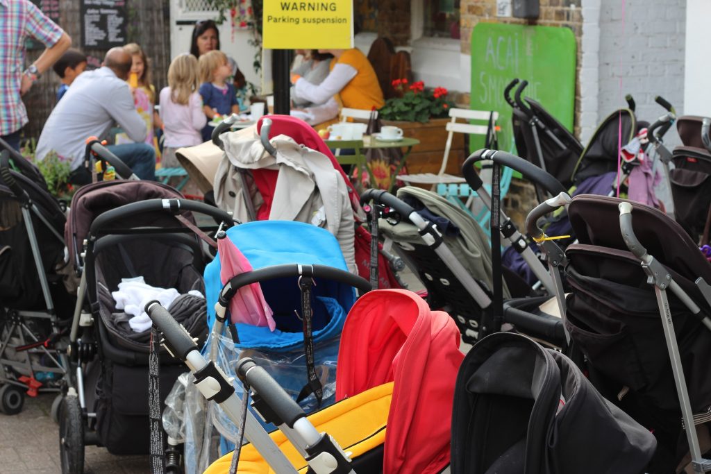 Young families having tea outside a cafe with buggies in the foreground