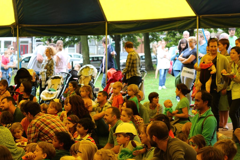 Parents and children watching a circus show in a Big Top at a TPP summer party